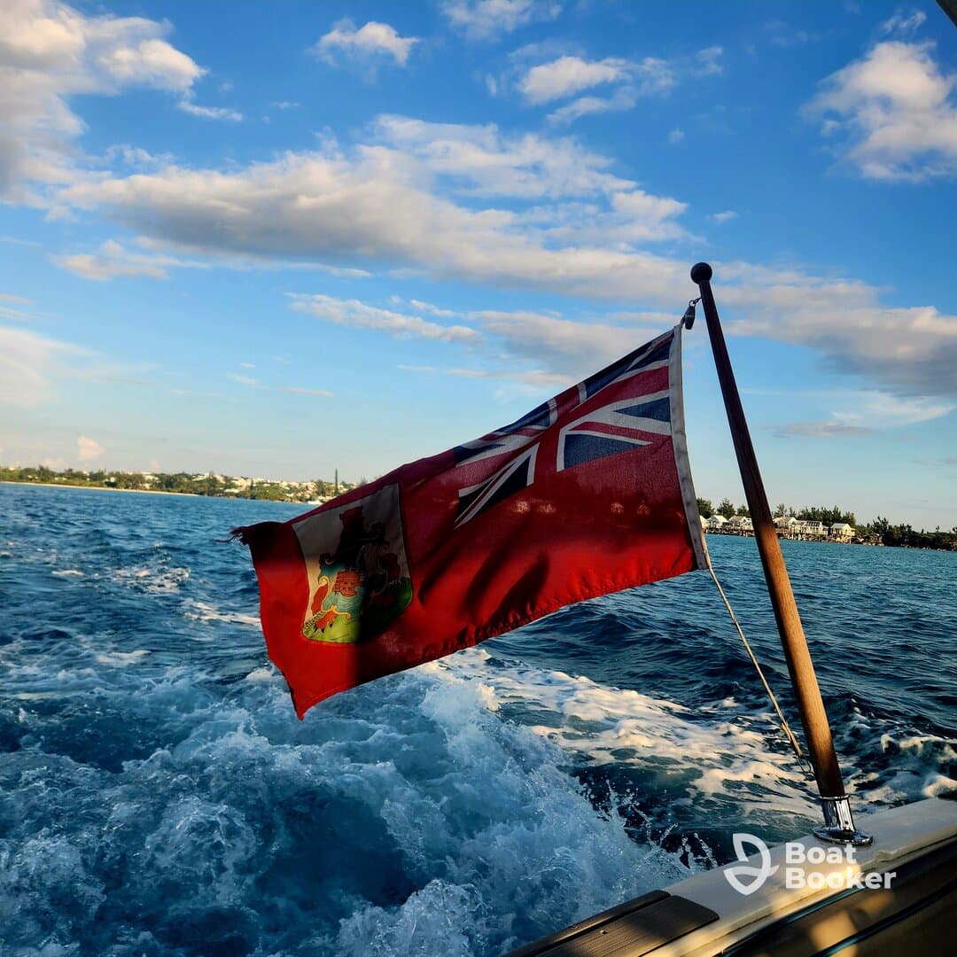 A vibrant shot of a boat's flag waving in the wind as it cruises through sparkling waters, showcasing the beauty of a day on the sea.