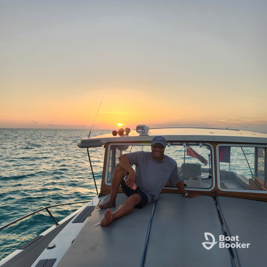 A man relaxes on the deck of a boat during a stunning sunset, capturing the essence of a perfect evening on the water.