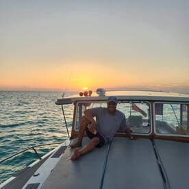 A man relaxes on the deck of a boat during a stunning sunset, capturing the essence of a perfect evening on the water.