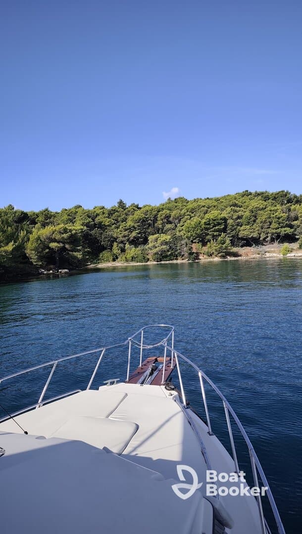 A serene view from the bow of a yacht, showcasing the tranquil waters and lush greenery of the coastline — perfect for peaceful boating adventures.