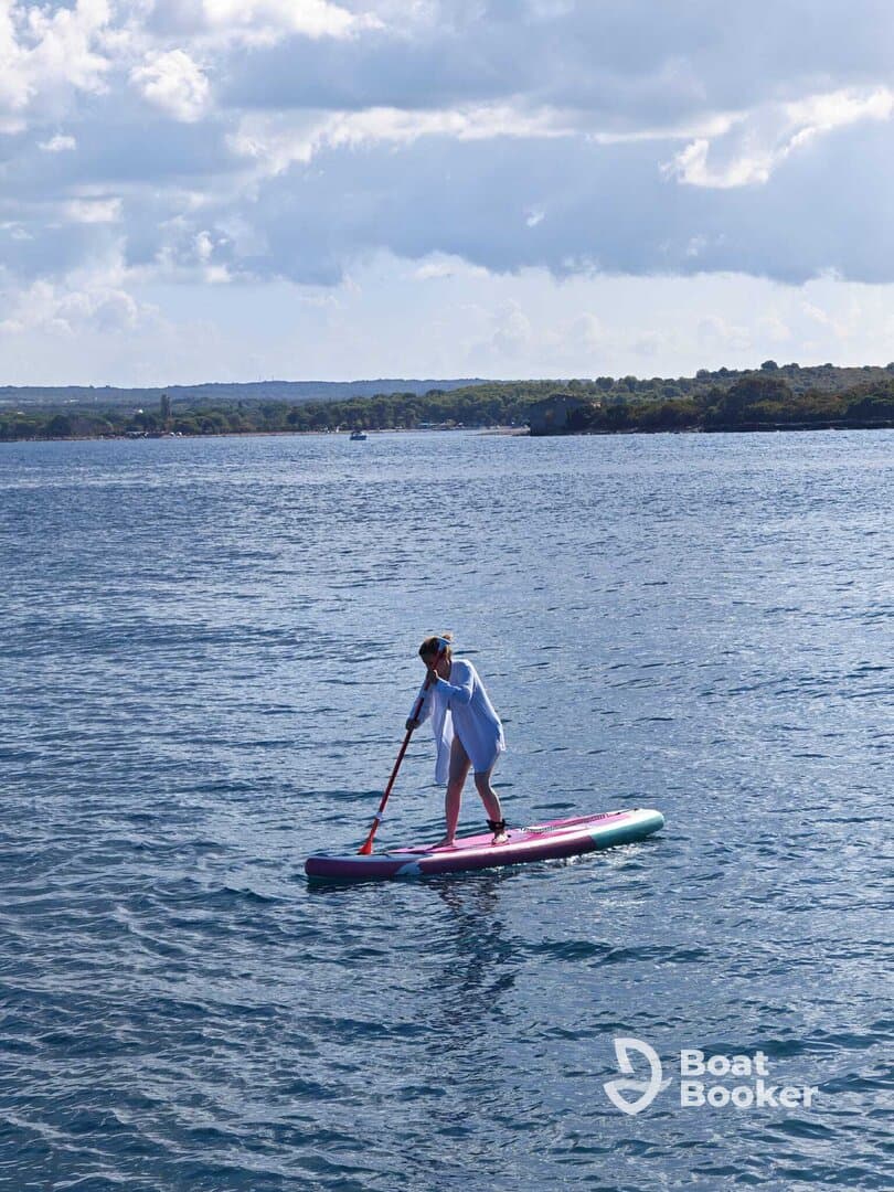 A woman enjoys paddleboarding on calm waters, showcasing the perfect blend of adventure and relaxation in a scenic outdoor setting.