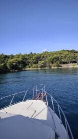 A serene view from the bow of a yacht, showcasing the tranquil waters and lush greenery of the coastline — perfect for peaceful boating adventures.