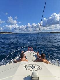Two friends relax on the bow of a boat, enjoying the sunny ocean views — a perfect moment for unwinding on the water.