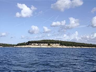 A picturesque view of a lush coastline and island, showcasing the natural beauty of the area — perfect for exploring by boat.