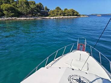 A stunning view from the front of a boat cruising through crystal-clear waters, surrounded by lush greenery and rocky shores — perfect for exploring coastal destinations.
