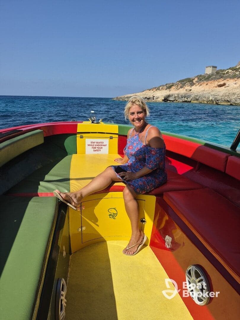 A woman relaxes inside a colorful boat, showcasing the vibrant seating area and inviting atmosphere for a day on the water.
