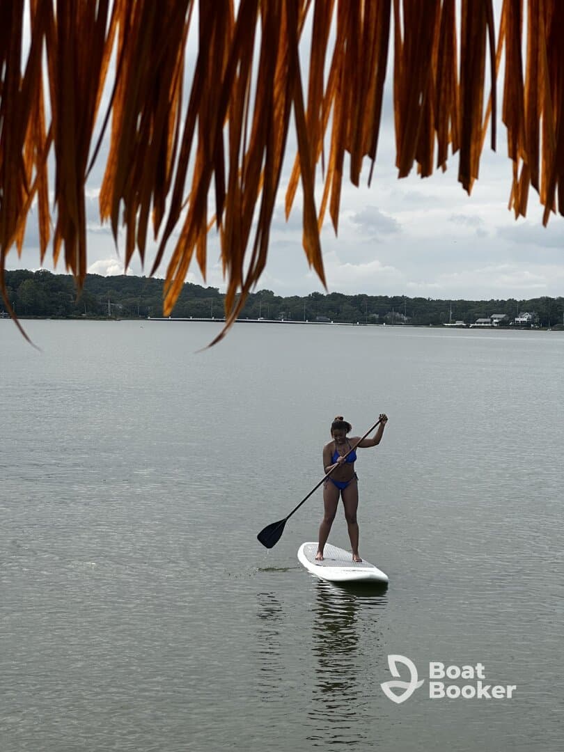 A woman paddleboards gracefully on calm waters, showcasing the fun and excitement of water sports. Perfect for adventure seekers looking to enjoy a day on the water.