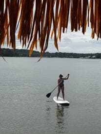 A woman paddleboards gracefully on calm waters, showcasing the fun and excitement of water sports. Perfect for adventure seekers looking to enjoy a day on the water.