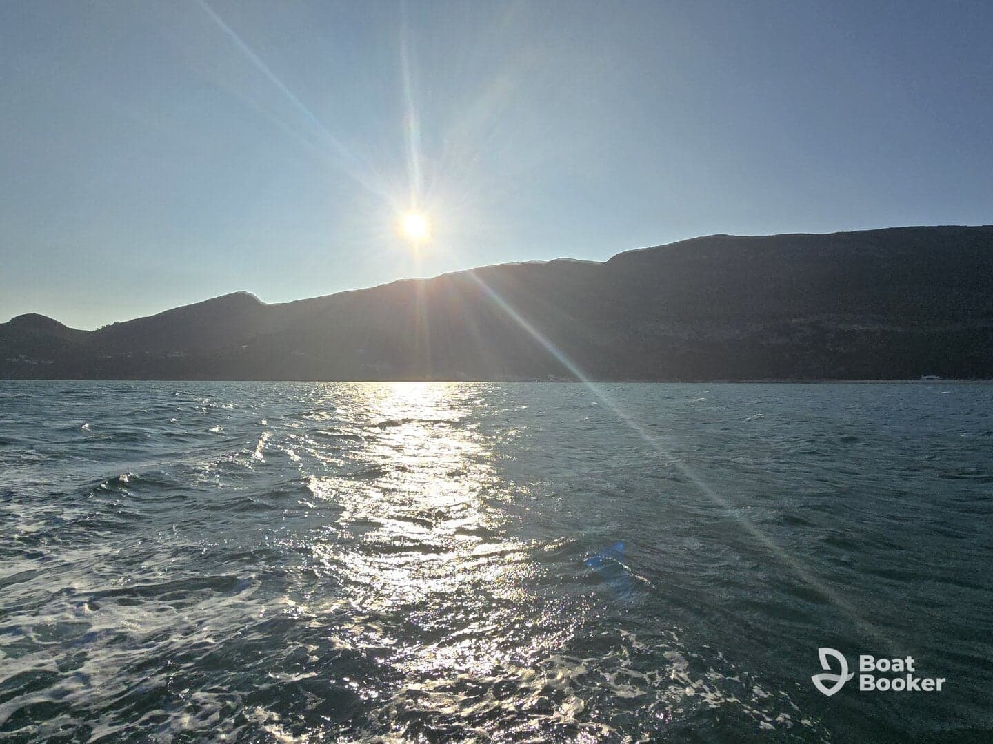 A stunning sunset over the mountains, reflecting on the water — a perfect moment for capturing the beauty of nature while on a boating adventure.