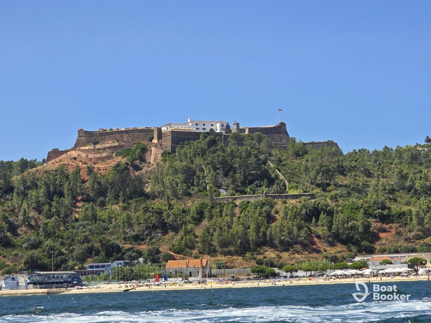 A stunning view of a historic fortress perched on a hillside, overlooking a beautiful beach and coastline — a perfect destination for sightseeing and exploration.