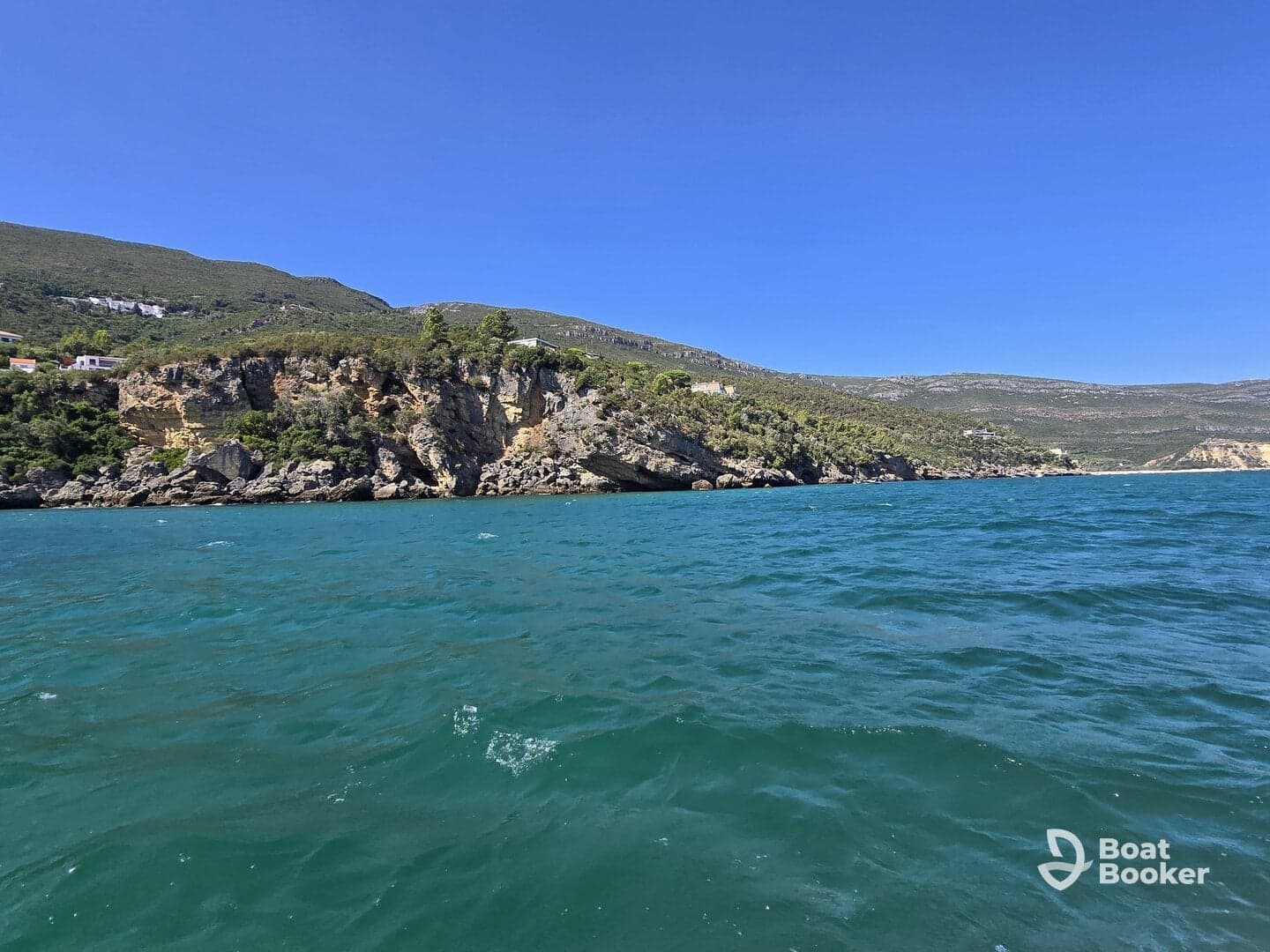 A stunning view of a rugged coastline with lush greenery and clear turquoise waters, perfect for showcasing the beauty of nature during a boating adventure.
