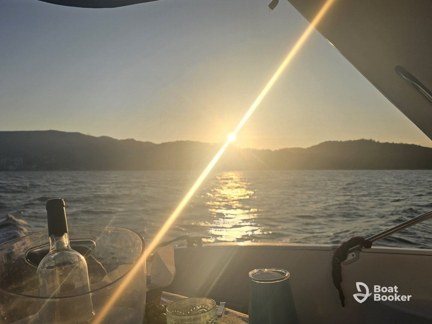 A serene sunset view from a boat, featuring a wine bottle and glass, creating a perfect ambiance for a relaxing evening on the water.