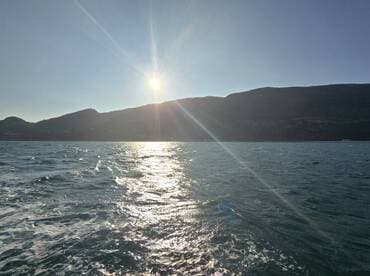 A stunning sunset over the mountains, reflecting on the water — a perfect moment for capturing the beauty of nature while on a boating adventure.