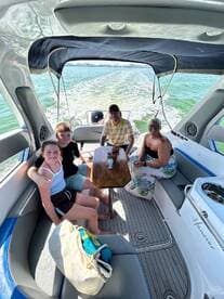 A family enjoys quality time inside a boat's cabin, seated around a table with drinks — perfect for relaxing during a day on the water.