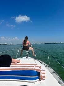 A young girl enjoys the sun while sitting at the bow of a boat, taking in the beautiful water views on a sunny day — perfect for a relaxing day on the water.