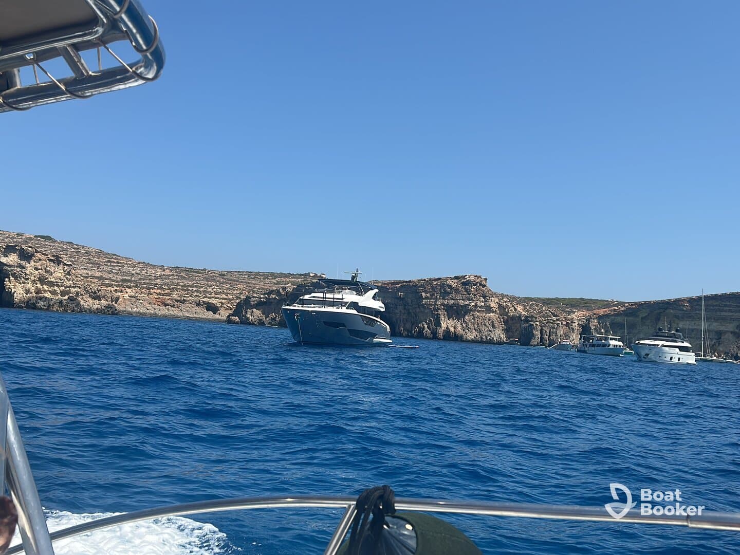 A stunning view of multiple yachts anchored near a rocky coastline, showcasing the beauty of maritime adventures.