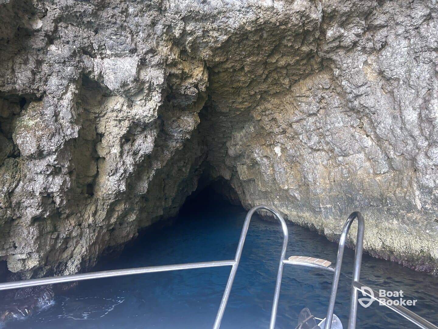 A stunning view of a cave entrance from a boat, showcasing the beautiful blue waters and rocky formations — perfect for exploring hidden gems during your aquatic adventures.