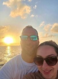 A couple enjoys a romantic sunset selfie on the water, capturing a perfect moment of celebration and togetherness.