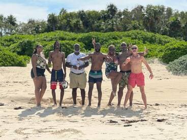 A lively group of friends poses for a fun photo on the beach, capturing the joy of their tropical getaway.