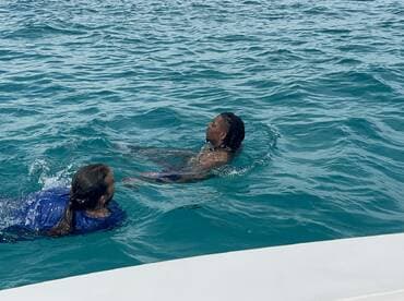 Two individuals enjoy a refreshing swim in vibrant turquoise waters, showcasing the fun and excitement of a day on the water.