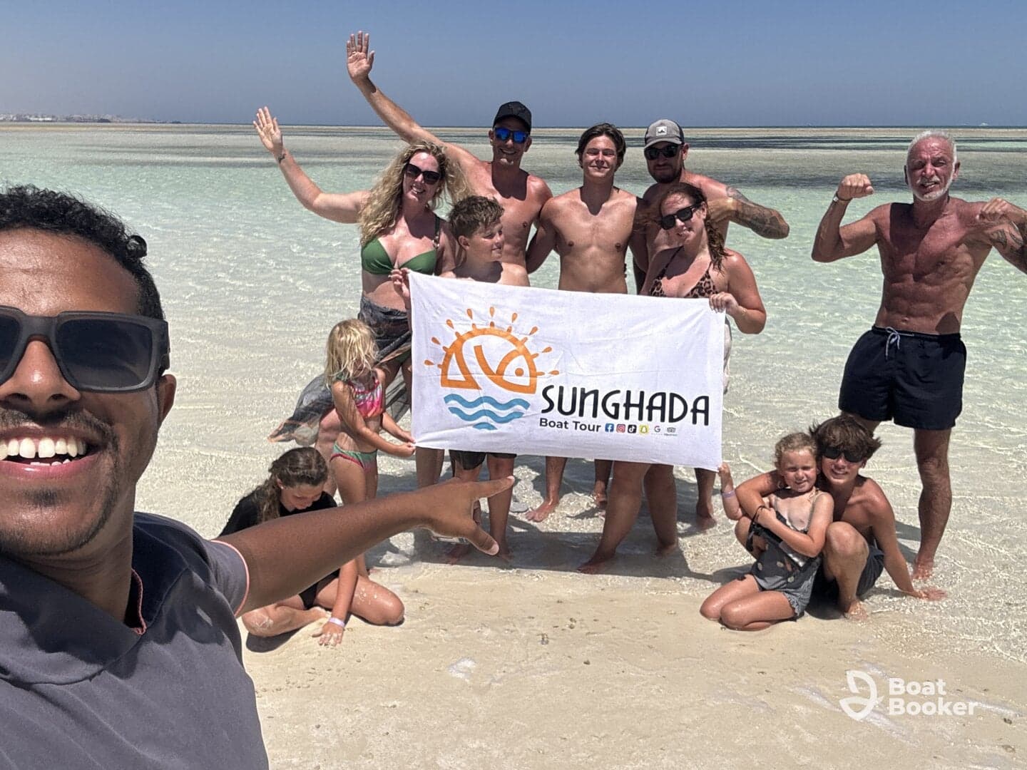 A joyful group poses on the beach holding a banner for Sunghada Boat Tour, capturing a memorable moment during their aquatic adventure.