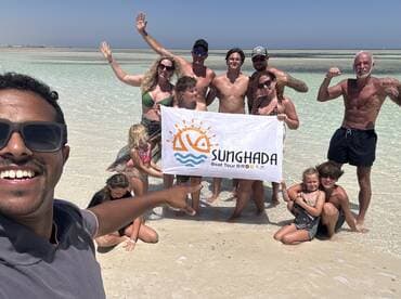 A joyful group poses on the beach holding a banner for Sunghada Boat Tour, capturing a memorable moment during their aquatic adventure.