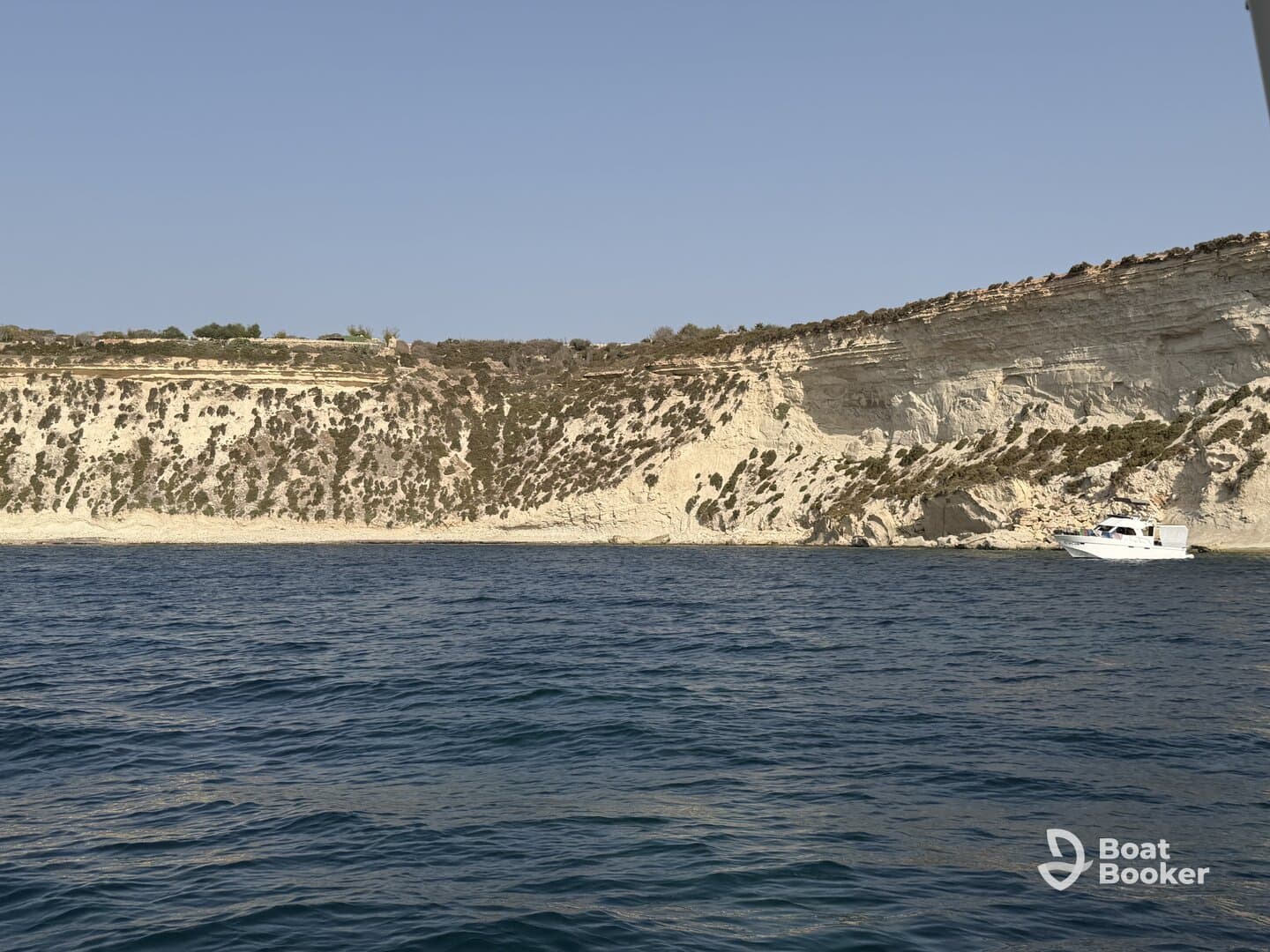 A picturesque view of a boat cruising along a stunning coastline, showcasing the natural beauty of the cliffs and clear waters.