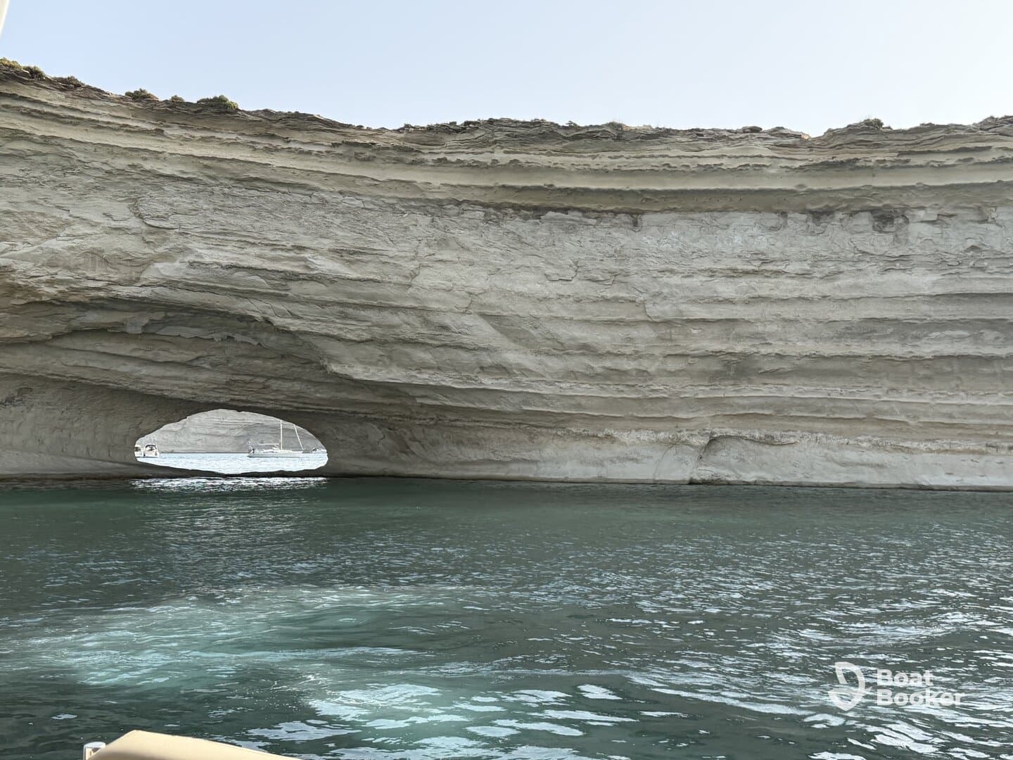 A stunning view of a natural rock arch along the coastline, showcasing the beauty of the surrounding waters — perfect for scenic boat tours.