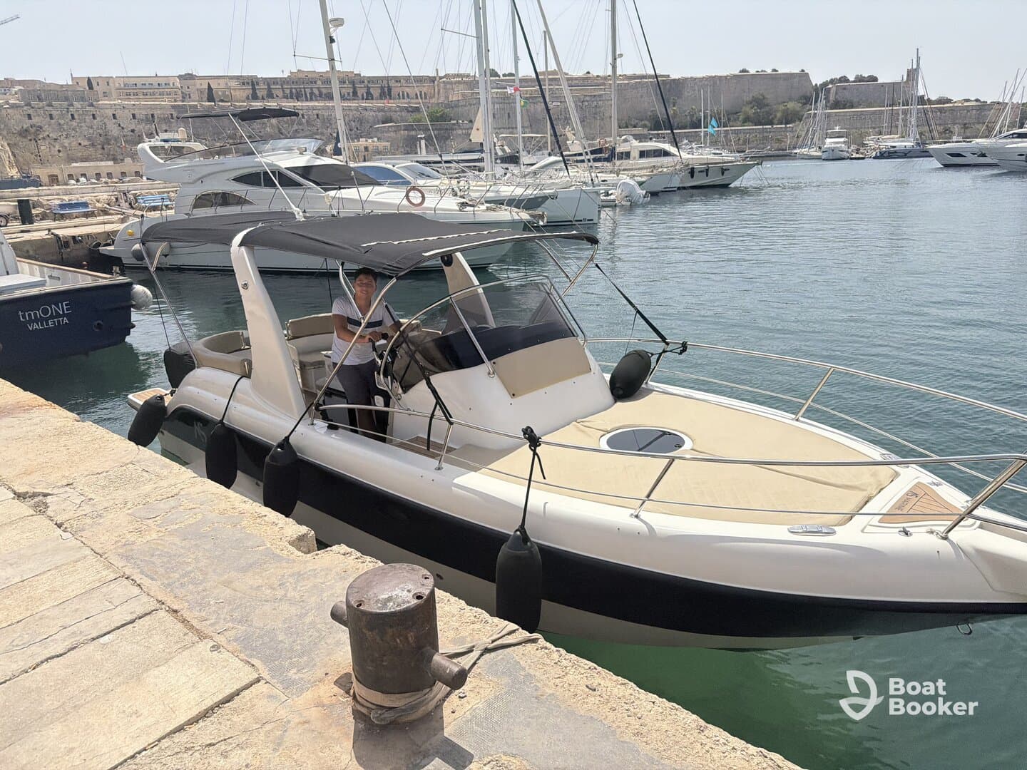 A sleek speedboat docked at the marina, with a person at the helm, showcasing a perfect blend of style and functionality for water adventures.
