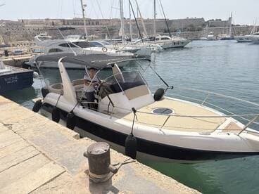 A sleek speedboat docked at the marina, with a person at the helm, showcasing a perfect blend of style and functionality for water adventures.