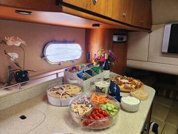 A beautifully arranged spread of snacks and drinks inside a boat's cabin, perfect for entertaining guests during a day on the water.