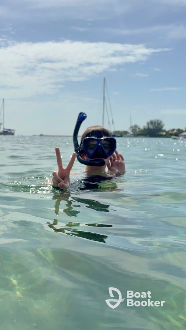 A child enjoys snorkeling in clear waters, flashing a peace sign while surrounded by a beautiful marine environment — a perfect moment for family adventures.