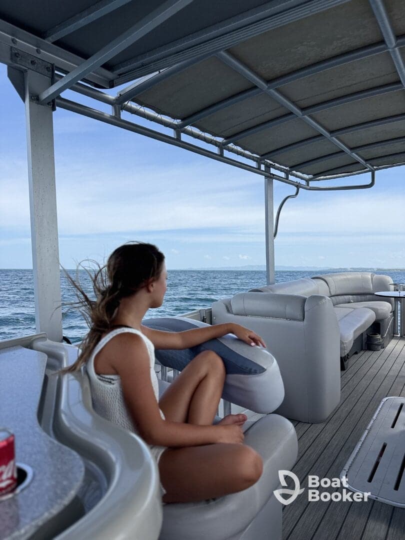 A young girl relaxes in the lounge area of a boat, enjoying the serene ocean view — perfect for family outings or peaceful retreats on the water.