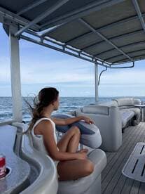 A young girl relaxes in the lounge area of a boat, enjoying the serene ocean view — perfect for family outings or peaceful retreats on the water.