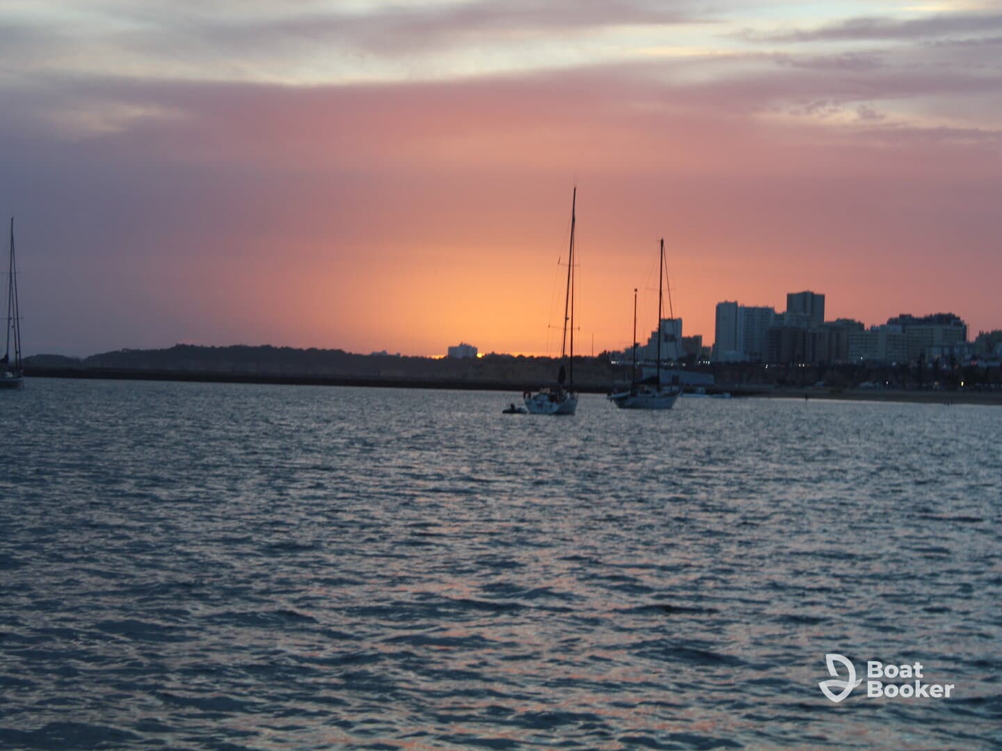 A serene sunset view featuring sailboats anchored in the harbor, creating a picturesque scene perfect for evening relaxation on the water.