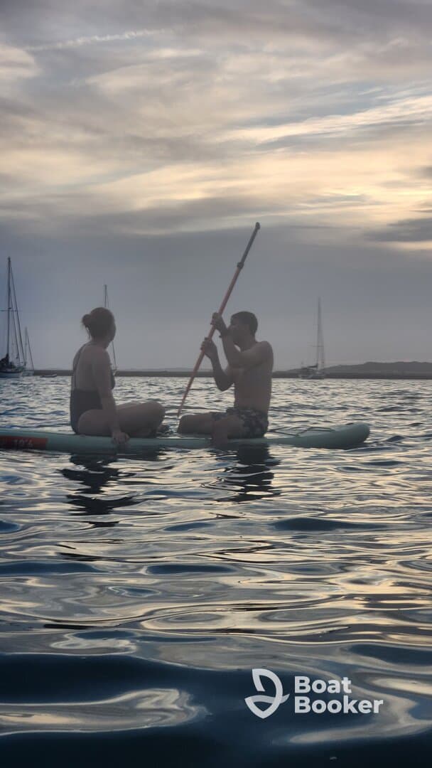 A couple enjoys paddleboarding during sunset, creating a serene and romantic atmosphere on the water.