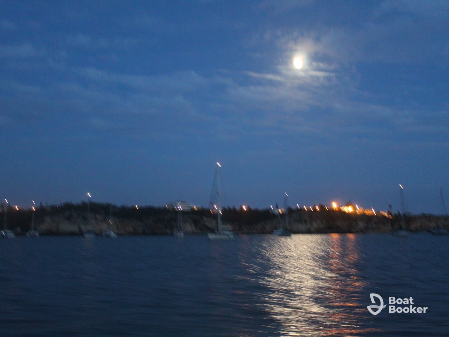 A nighttime view of a harbor with distant lights and a full moon, but the image is unclear and lacks focus.