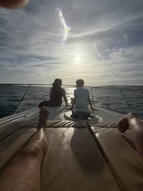 A couple enjoys a serene sunset view from the bow of a boat, creating a perfect moment for relaxation and connection on the water.