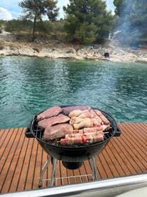 A close-up of a grill loaded with various meats, perfect for a barbecue on the water, showcasing the ideal amenities for a fun day out on a boat.