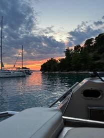 A serene sunset view from the deck of a boat, showcasing the tranquil waters and surrounding landscape — perfect for evening cruises and relaxation.