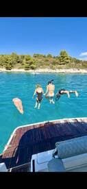 A group of friends joyfully jumps into the crystal-clear waters from a boat, capturing the essence of summer fun and adventure on the water.