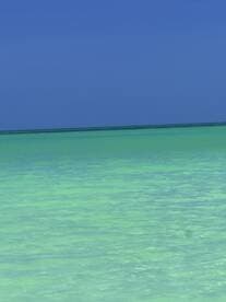 An unclear image of turquoise waters under a clear blue sky, lacking identifiable subjects or details.