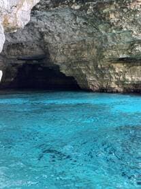 A stunning view of a cave with crystal-clear turquoise waters, perfect for exploring hidden gems during a boating adventure.