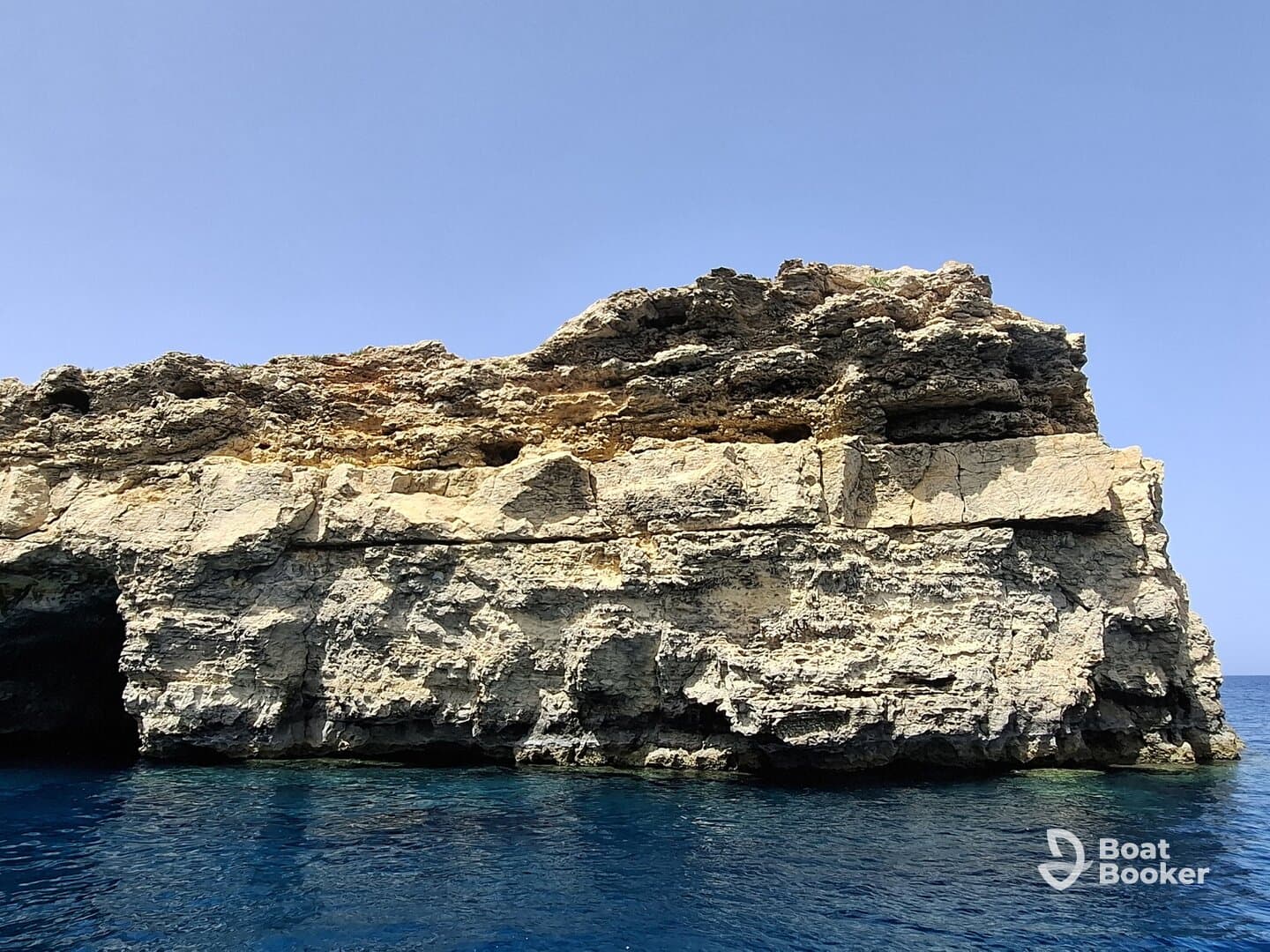 A stunning view of a rocky coastline against the clear blue waters, perfect for showcasing the natural beauty of the area.