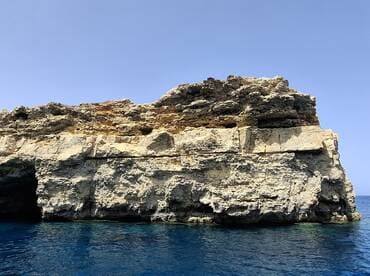 A stunning view of a rocky coastline against the clear blue waters, perfect for showcasing the natural beauty of the area.