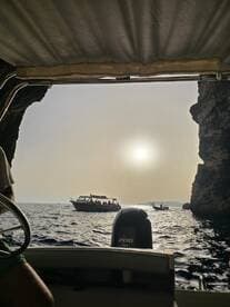 A scenic view from a boat, capturing the sun setting over the water with another boat in the distance — perfect for showcasing the beauty of coastal adventures.
