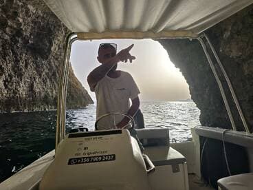 A boat captain navigates through a scenic cave, showcasing the stunning ocean views — an ideal moment for adventure seekers exploring coastal wonders.