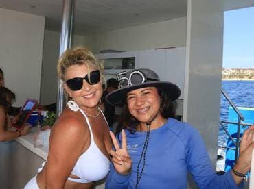 Two women pose happily aboard a boat, showcasing a fun and celebratory atmosphere — perfect for memorable outings with friends.