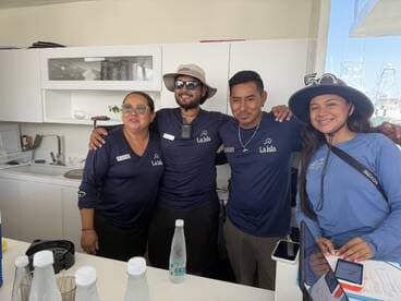 A friendly group of staff members poses together in a boat's interior, showcasing their welcoming atmosphere and readiness to assist guests on their maritime adventures.