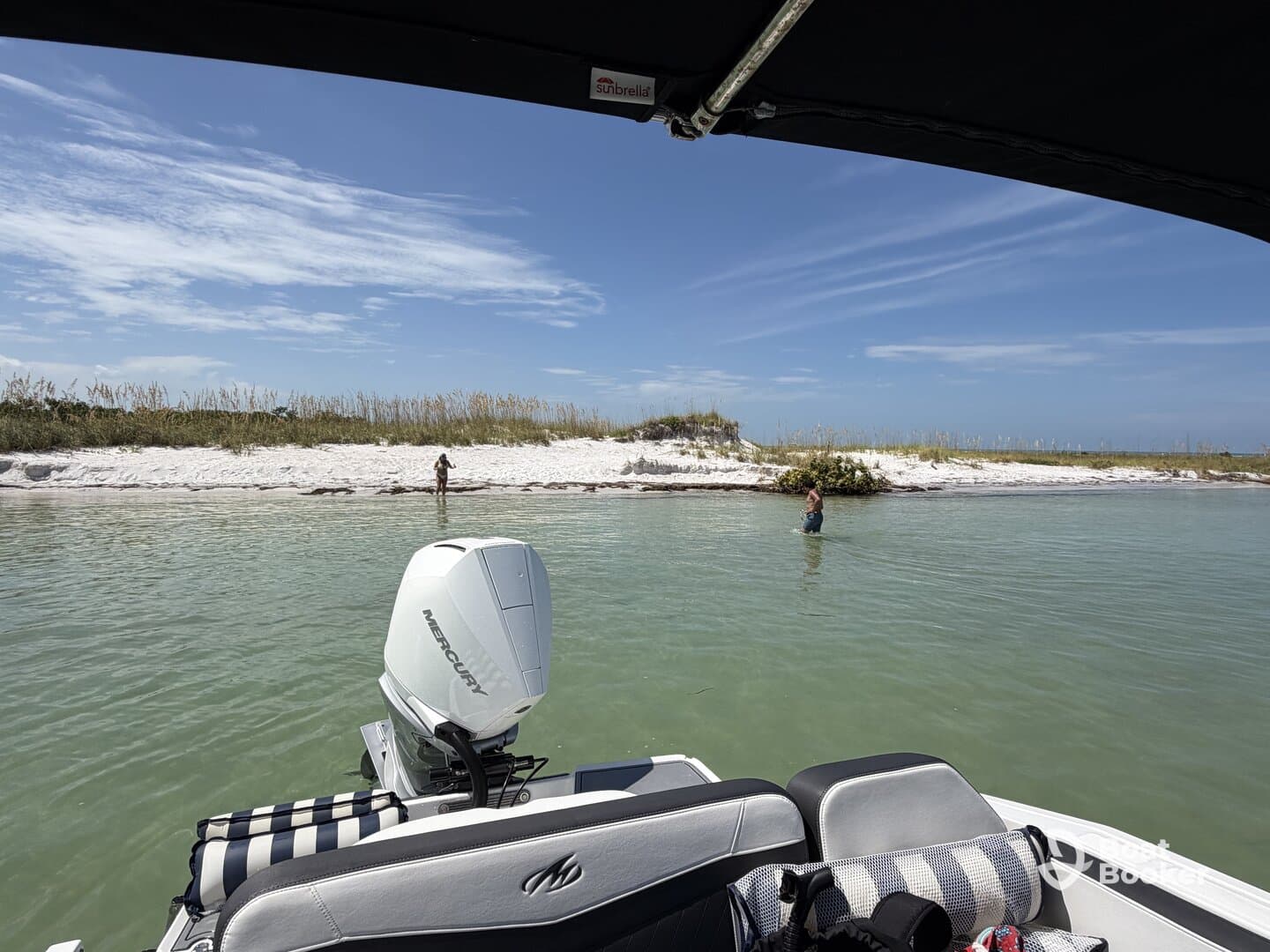Guests enjoy a relaxing day at a sandbar, with one person swimming in the clear waters while the boat is anchored nearby — a perfect beach getaway.